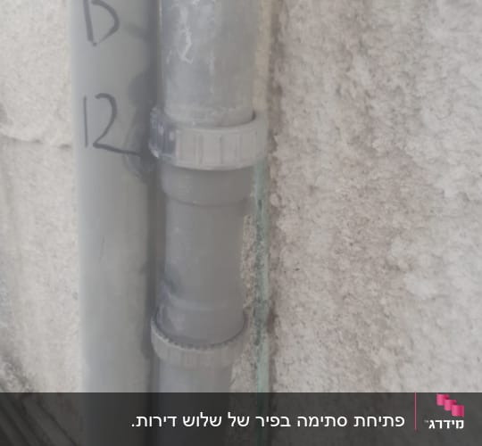 צינור פלסטיק אפור עם מחבר על קיר